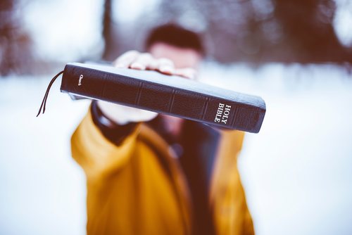 A man with a Bible in his outstretched right hand.