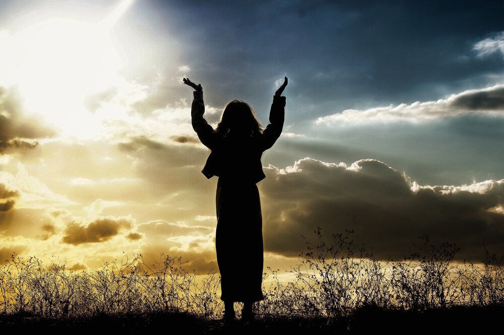 A woman with arms raised in prayer to God