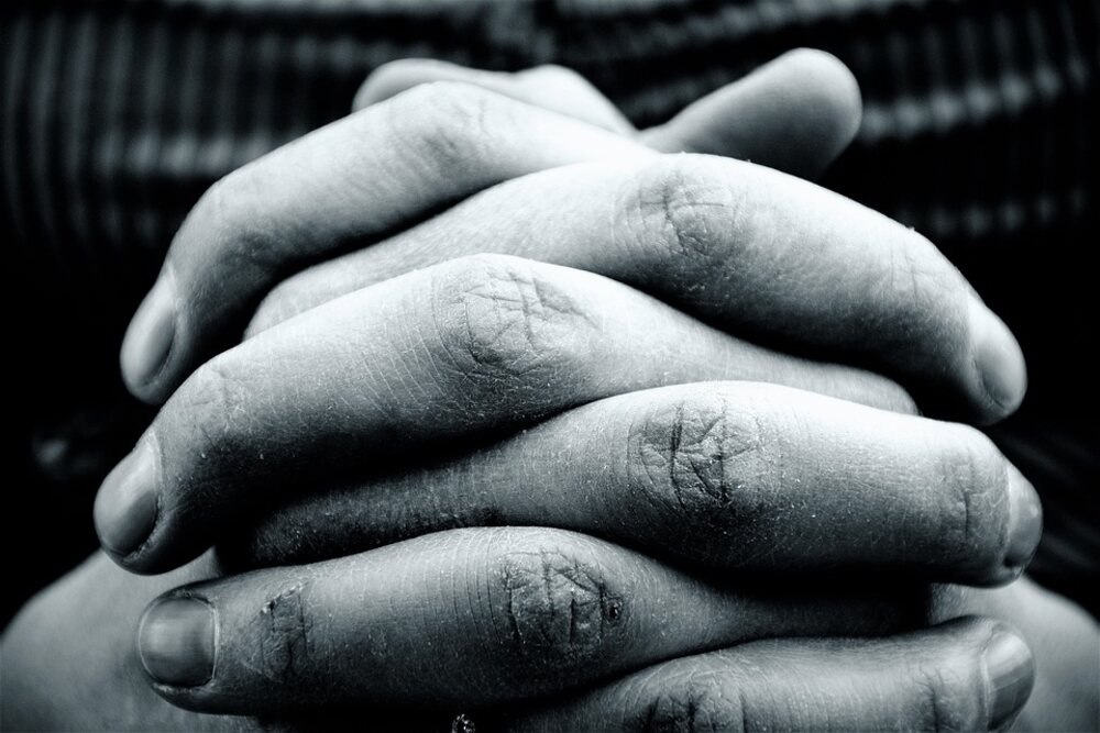 A pair of hands clasped prayerfully signifying faith in God .