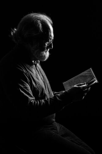 A wise old man reads a bible by candlelight.