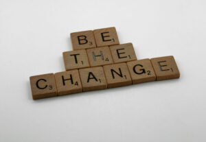 The phrase “Be the change” spelled in scrabble letters.